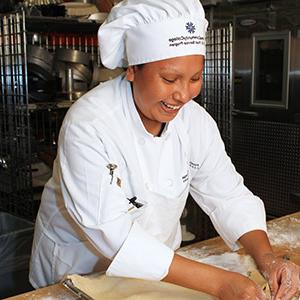 皮马社区学院 culinary program student wearing chef's jacket and working in kitchen